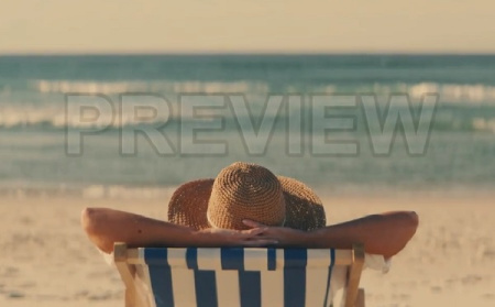 دانلود فوتیج زن در حال استراحت روی صندلی ساحل
